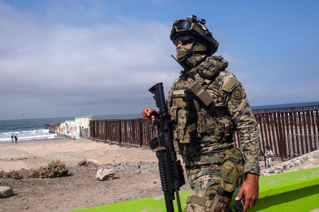 Un oficial de la Secretaría de la Marina hace guardia en Playas de Tijuana, justo en la frontera entre Estados Unidos y México. Foto Afp