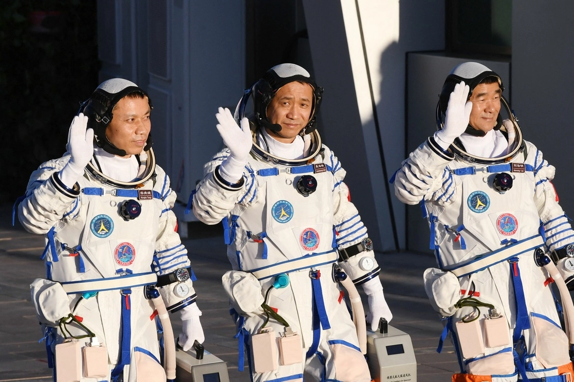 Los astronautas Nie Haisheng (centro), Liu Boming (der.) y Tang Hongbo saludan durante una ceremonia de salida antes de abordar la nave espacial Shenzhou-12 en un cohete portador Long March-2F en el Centro de lanzamiento de satélites de Jiuquan en el desierto de Gobi en el noroeste de China, el 17 de junio de 2021. Foto Afp