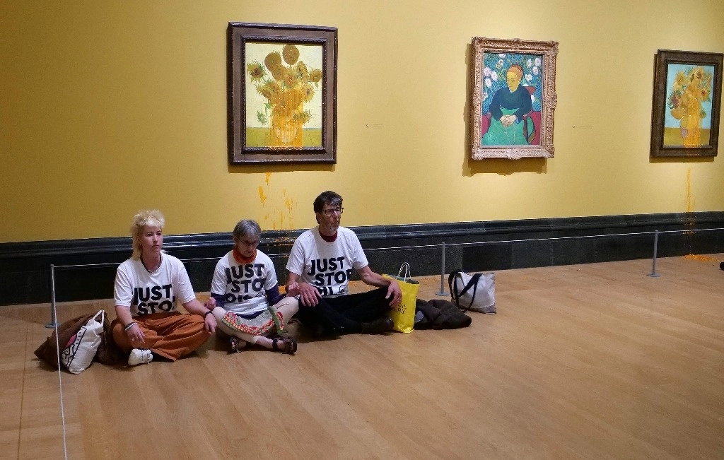 Integrantes del grupo de campaña climática Just Stop Oil sentados en el suelo bajo los "Girasoles" de Vincent van Gogh después de arrojar sopa de tomate sobre dos pinturas en la Galería Nacional en el centro de Londres el 27 de septiembre de 2024. Foto Afp