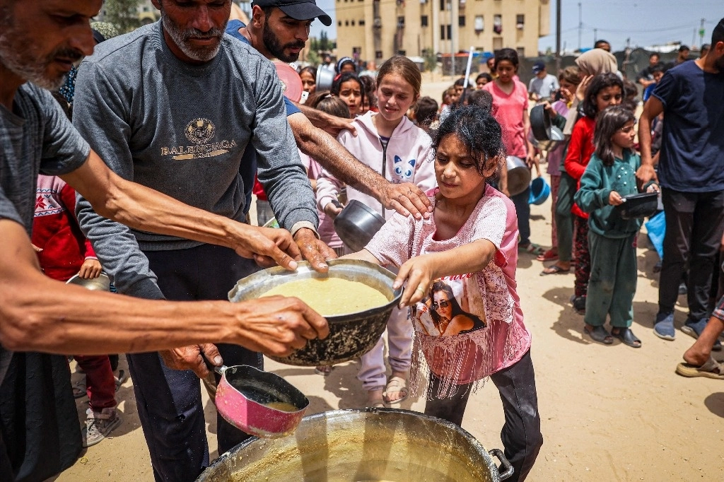 Niños desplazados palestinos hacen fila para recibir comida en Rafah, al sur de la franja de Gaza. Foto Afp 