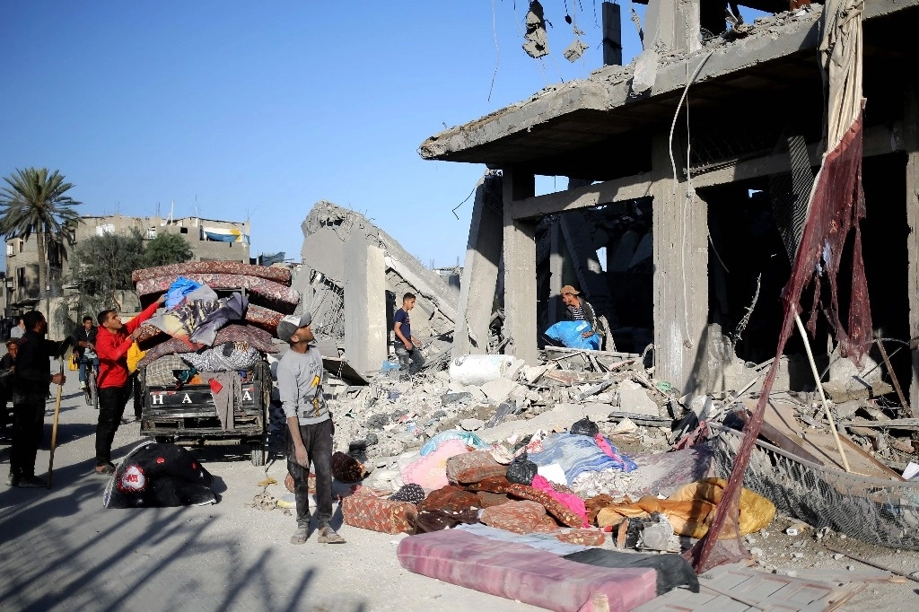 Palestinos recolectan sus pertenencias luego de un ataque aéreo israelí ocurrido en la ciudad de Rafah, en el sur de la franja de Gaza. Foto Afp
