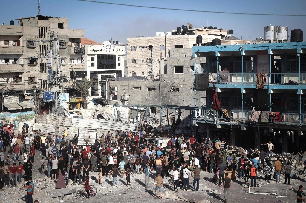Palestinos se reúnen en el patio de la escuela bombardeada por Israel en el campo de refugiados Nuseirat. Foto Afp