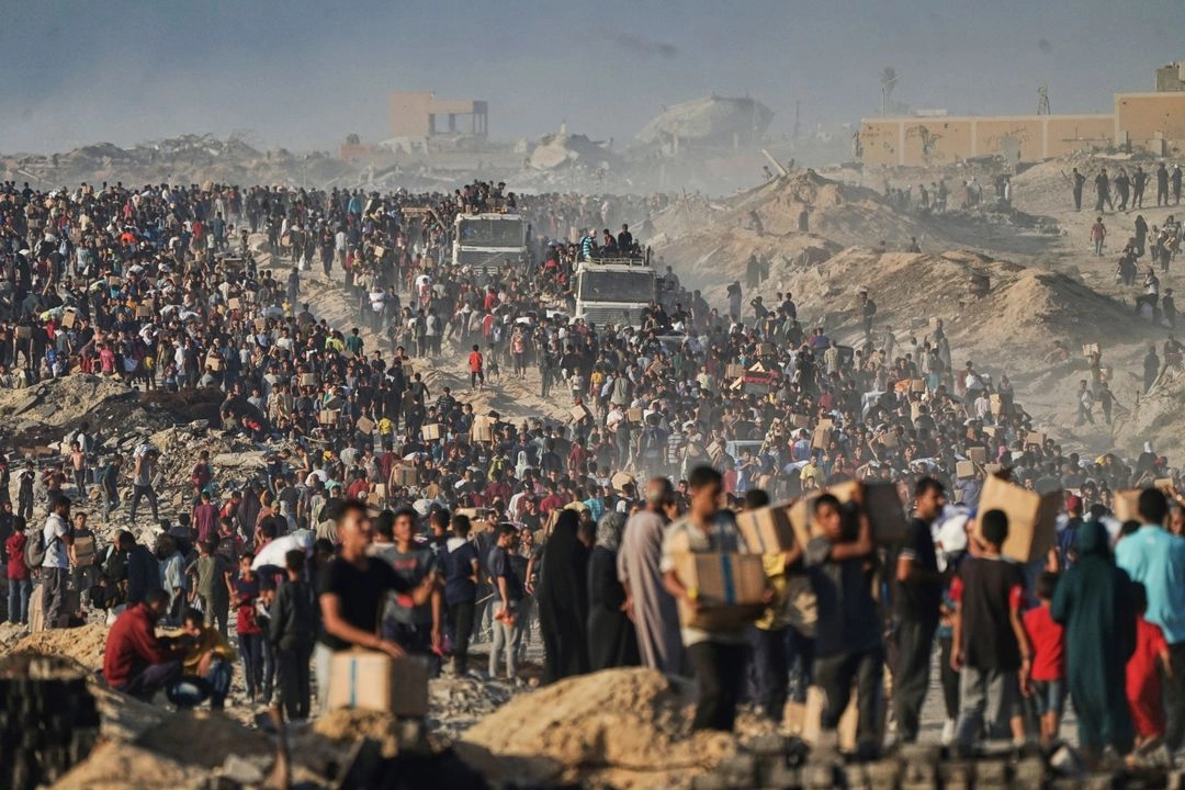 Palestinos llevan sacos y cajas de alimentos y ayuda humanitaria descargados de un convoy del Programa Mundial de Alimentos que se dirigía a la ciudad de Gaza, en el norte de la Franja de Gaza, el lunes 16 de junio de 2025.