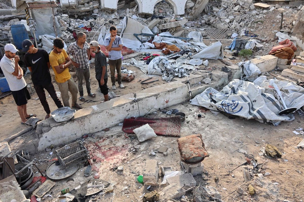 Palestinos inspeccionan los daños en un campamento para desplazados internos, tras ser alcanzado por un ataque israelí nocturno, en el barrio norteño de Al-Rimal, en la ciudad de Gaza, el 15 de julio de 2025. 