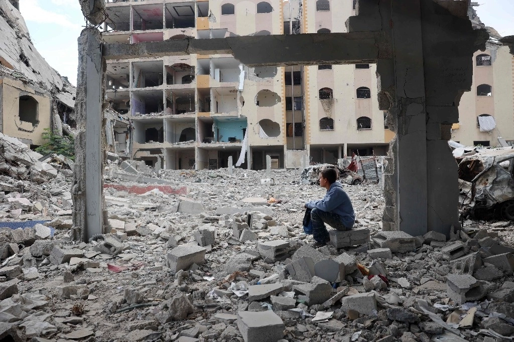 Un niño palestino se sienta en medio de edificios destruidos en Nuseirat, en el centro de la franja de Gaza. Foto Afp