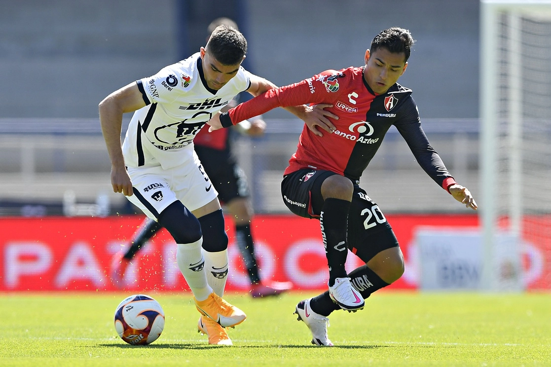 Johan Vásquez de Pumas e Ían Jairo Torres del Atlas disputan el esférico en la cancha del Olímpico Universitario. Foto LIGA MX/Imago 7 