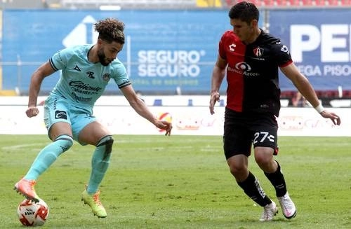 César Huerta cubre el esférico ante la marcación del atlista Jesús Angulo durante el partido de ayer en el estadio Jalisco. Foto Afp