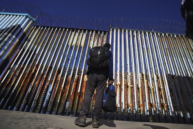 Migrante observa el muro fronterizo entre México y EU en la ciudad de Tijuana, BC. Foto Ap