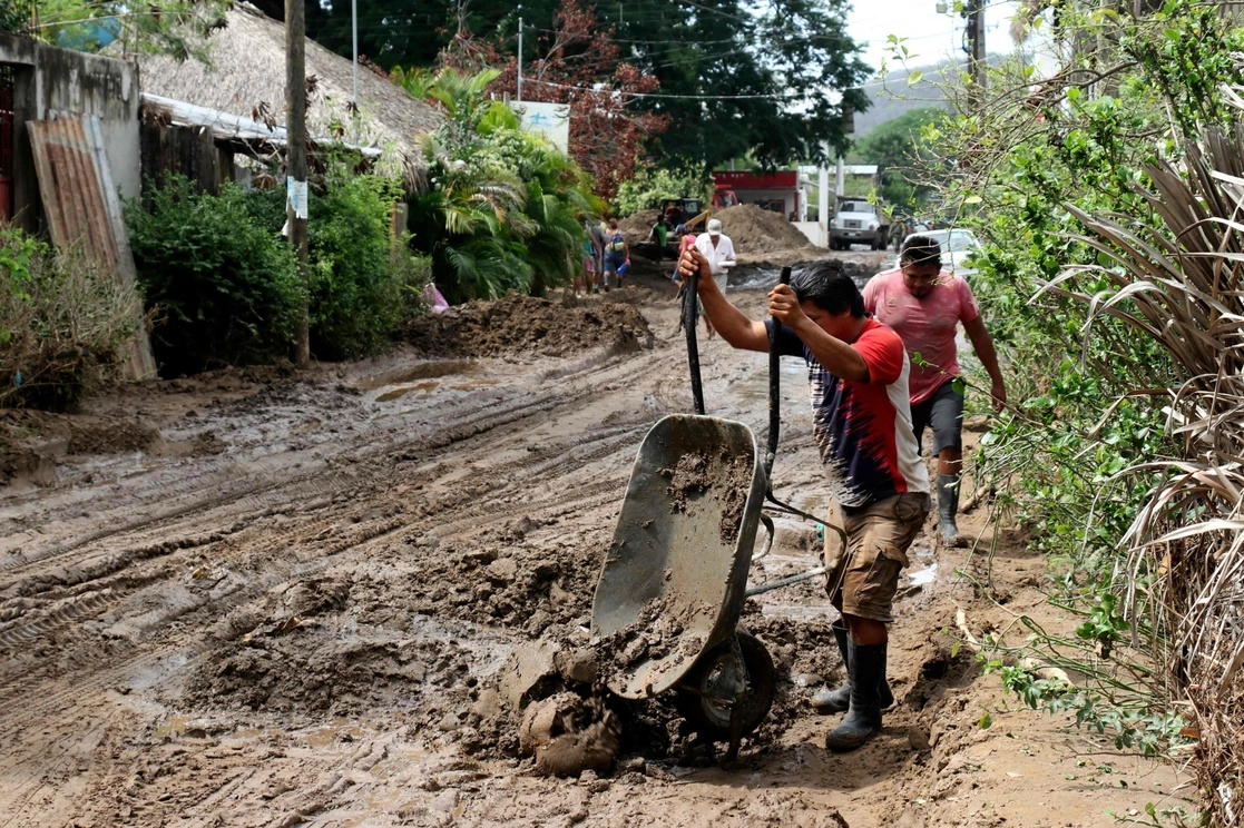 Un hombre limpia una calle cubierta de lodo en Huatulco, Oaxaca, el 1 de junio de 2022. Foto Afp
