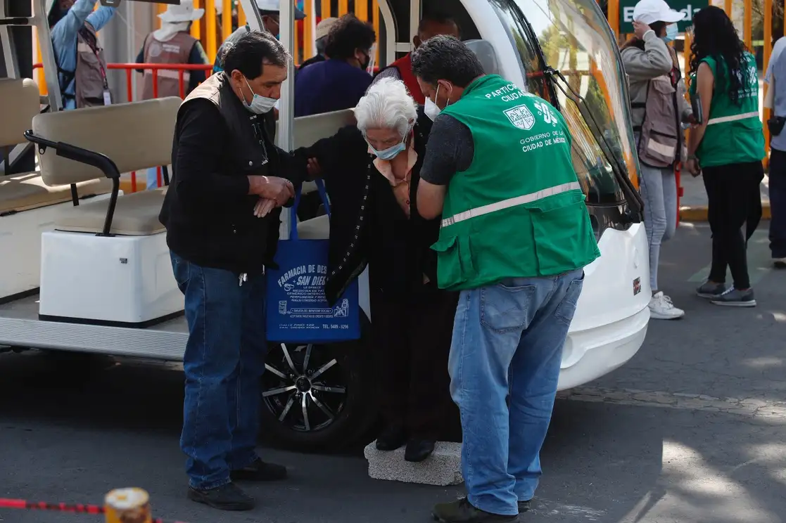 Personal del GCDMX ayuda a una adulta mayor a bajar de un transporte implementado por la alcaldía de Xochimilco, para que ingrese a la Preparatoria 1 y reciba su vacuna contra Covid-19, en la alcaldía Xochimilco, Ciudad de México, el 4 de marzo de 2021. Foto Cristina Rodriguez
