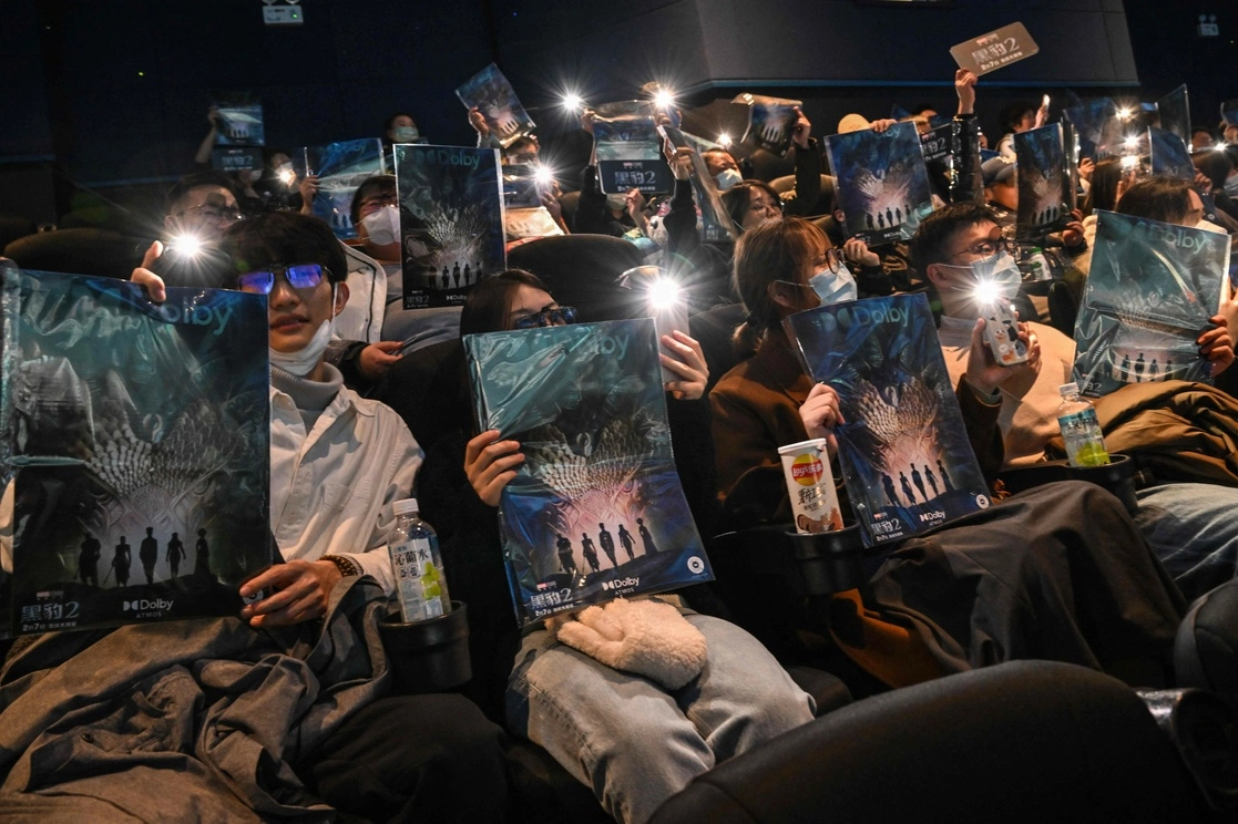 Jóvenes sostienen un cartel mientras esperan para ver la cinta ‘Black Panther: Wakanda Forever’ en un cine de Shanghái, el 6 de  febrero de 2023. Foto Afp
