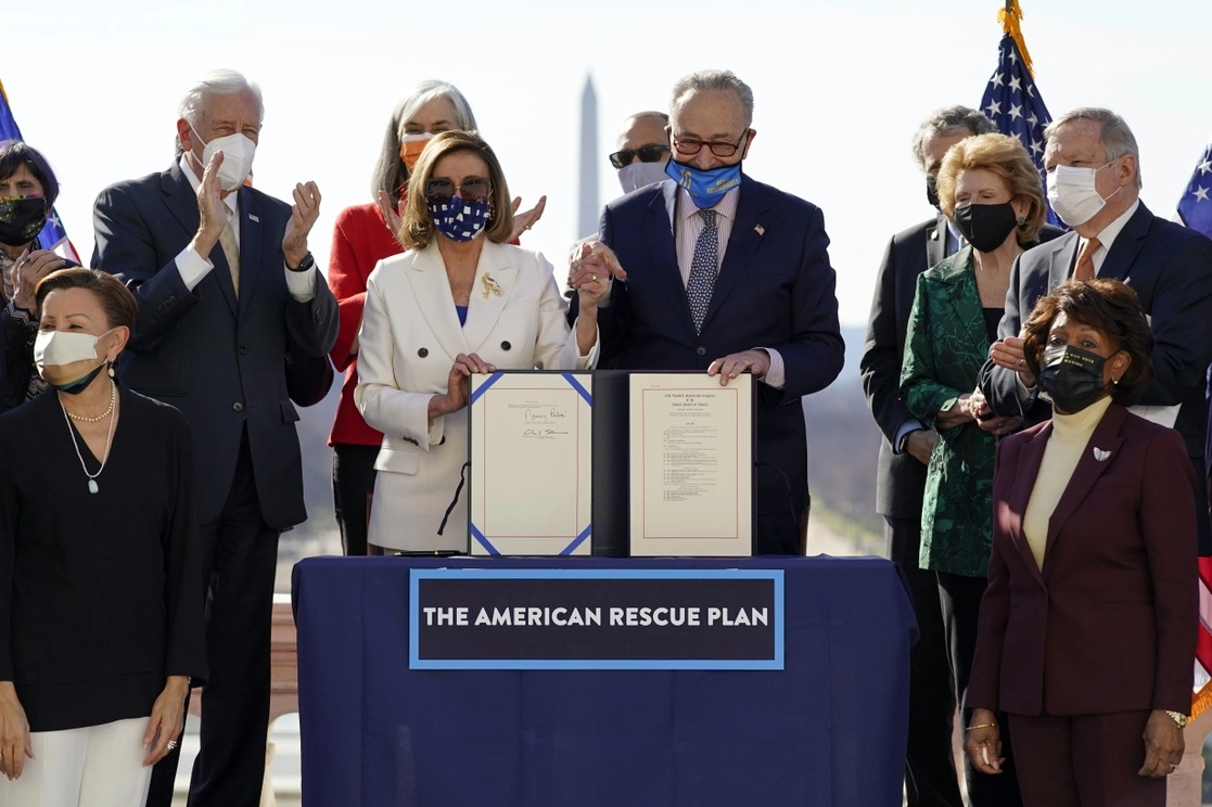 La presidenta de la Cámara de Representantes, Nancy Pelosi, y el líder de la mayoría del Senado, Chuck Schumer (al centro, tomados de la mano), presentan el Plan de Rescate de Estados Unidos, que el viernes será promulgado ley por el presidente Biden, el 10 de marzo de 2021. Foto Ap