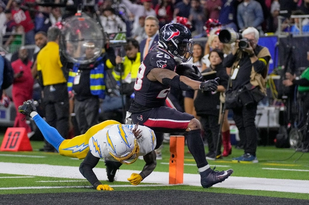 El corredor de los Houston Texans, Joe Mixon (28), anota un touchdown mientras el esquinero de los Los Angeles Chargers, Kristian Fulton, defiende durante la segunda mitad de un partido de comodines de la NFL el sábado 11 de enero de 2025 en Houston.  Foto Ap