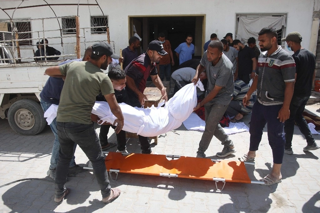 Palestinos cargan el cuerpo de un gazatí muerto durante un ataque israelí ocurrido ayer en el campo de refugiados de Jabalia, en el norte de Gaza. Foto Afp 
