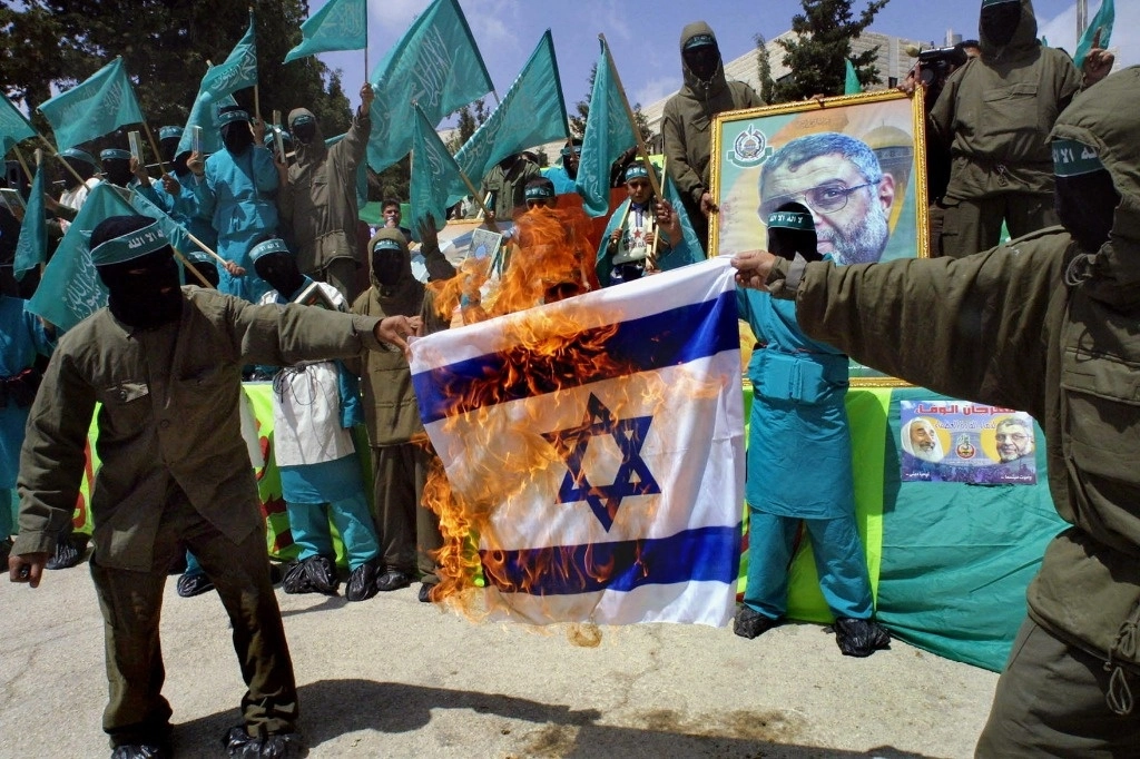 Militantes de Hamas queman una bandera israelí frente a la Universidad de Hebrón, el 3 de mayo de 2004, mientras fuerzas de Tel Aviv continuaron ayer sus ataques en la franja de Gaza. Foto Afp