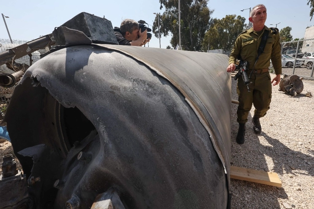 Funcionario militar israelí posa junto a los restos de un misil balístico iraní. Foto Afp



