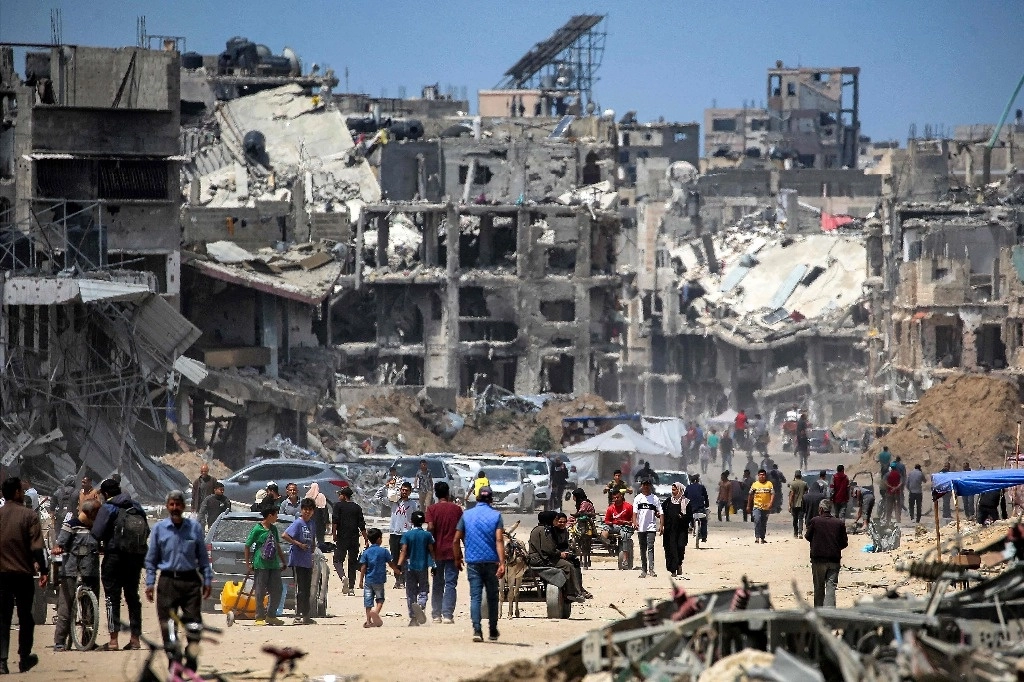 Habitantes de Gaza se desplazan entre los edificios destruidos por misiles lanzados desde Israel, en su guerra contra Hamas iniciada el pasado 7 de octubre. Foto Afp 