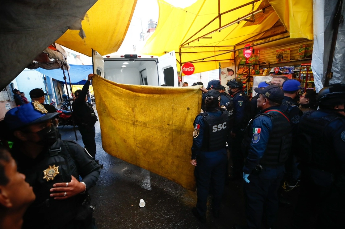 Policías cubren el cuerpo de un joven que fue ejecutado en un taller de motocicletas en la calle Tenochtitlan. Foto Víctor Camacho