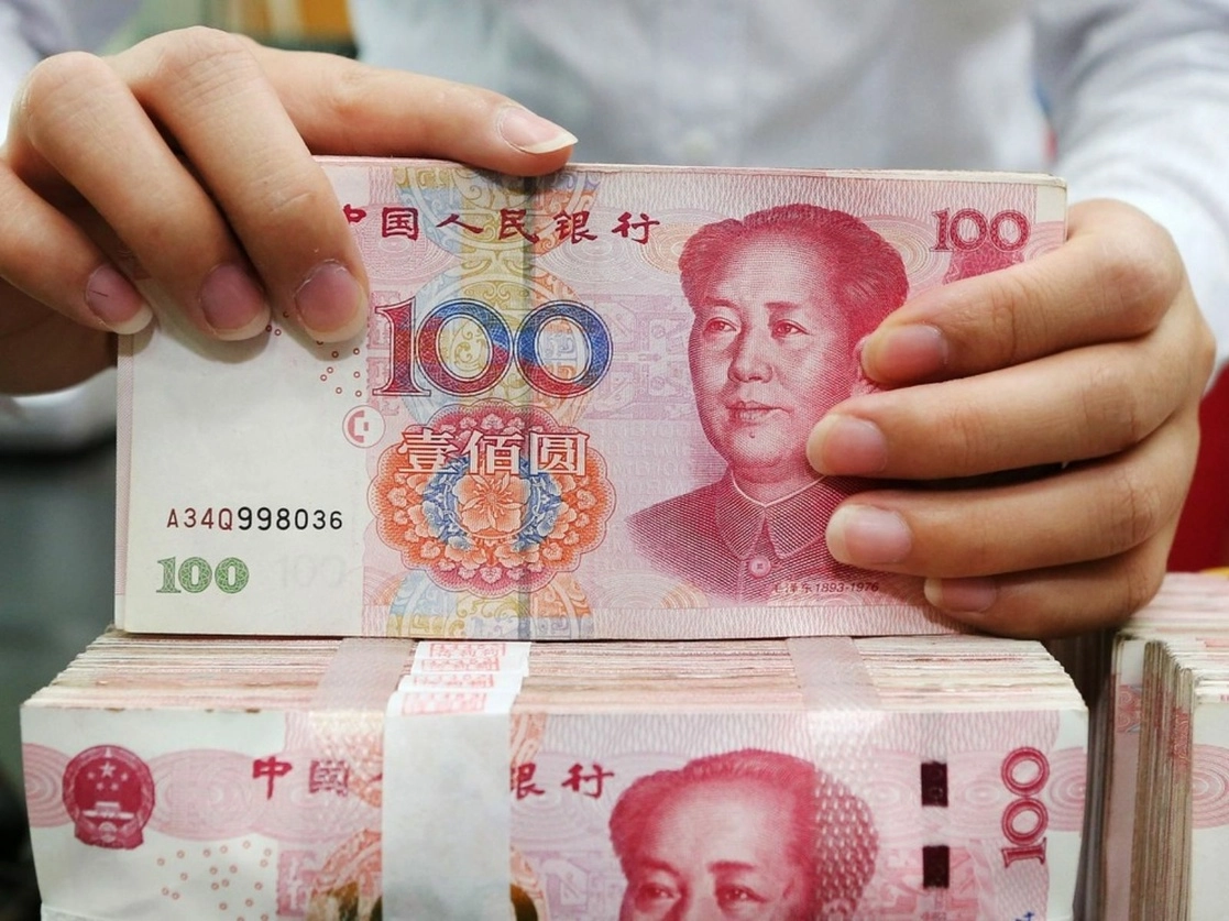 Una empleada cuenta billetes de cien yuanes en un banco chino. Foto Afp / Archivo
