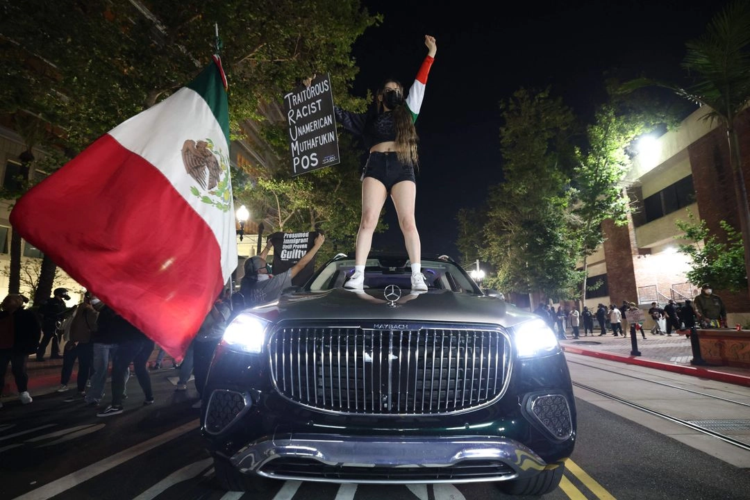 Una mujer se sube a un auto con una bandera mexicana y una pancarta mientras los manifestantes se reúnen cerca del Edificio Federal en Santa Ana, California, tras los informes de redadas del Servicio de Inmigración y Control de Aduanas (ICE) el 9 de junio de 2025. Foto 