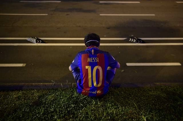 Seguidor del Barcelona usa la playera con el nombre y número de Lionel Messi a fuera del Camp Nou. Foto Afp