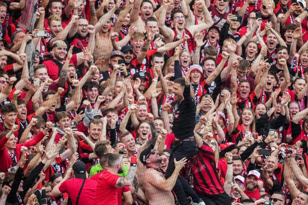 El Bayer Leverkusen, campeón de la liga alemana de manera matemática desde hace cinco semanas, se impuso 2-1 al Augsburgo y se convirtió así en el primer equipo en acabar invicto una Bundesliga. En la imagen, el entrenador Xabi Alonso festeja con los aficionados, el 18 de mayo de 2024. Foto Ap