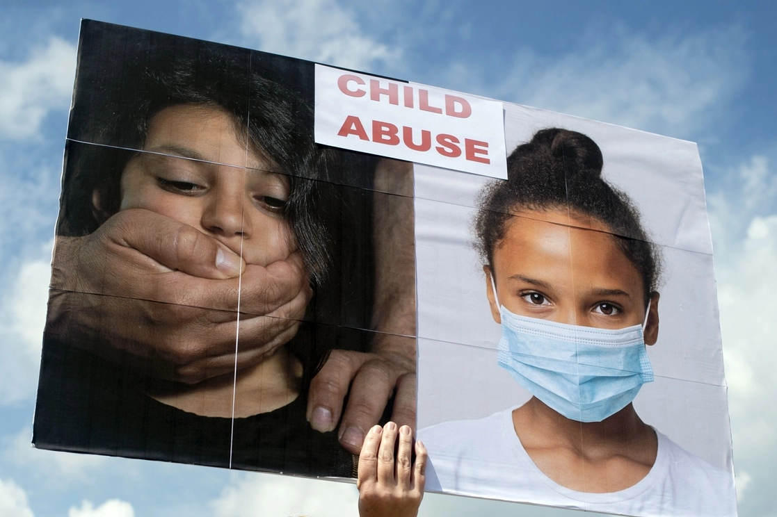 Una residente de Swartz Creek sostiene un cartel que califica el uso de máscaras como abuso infantil. Foto Ap