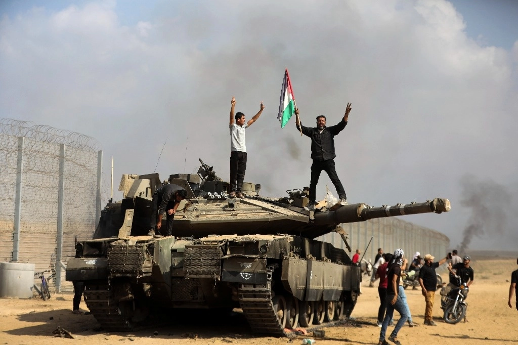 Palestinos ondean su bandera nacional y celebran junto a un tanque israelí destruido en la valla de la franja de Gaza al este de Khan Younis. Foto Ap