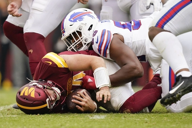 Greg Rousseau (de blanco) taclea al mariscal de campo de los ‘Commanders’, Sam Howell. Foto Ap