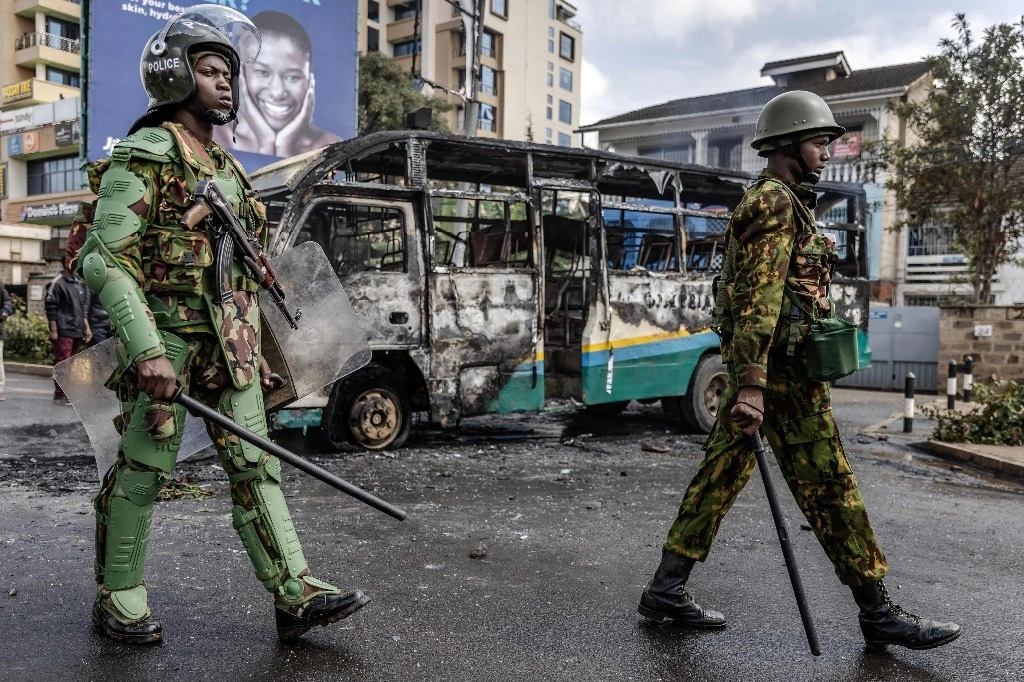 Un oficial de policía de Kenia camina junto a un autobús quemado por manifestantes durante los disturbios en Nairobi el 2 de mayo de 2023.Foto Afp