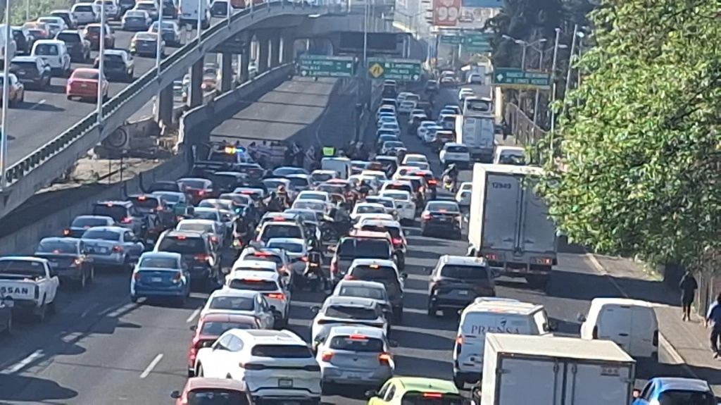 Decenas de usuarios de la importante vialidad circulan a vuelta de rueda, en dónde trabajadores levantan cartulinas con la leyenda: no más abusos de autoridad. Foto 'La Jornada'