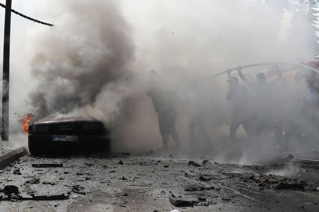 Bomberos libaneses apagan las llamas en un auto luego de un ataque israelí en la ciudad de Sidón, al sur de Líbano. Foto Afp 