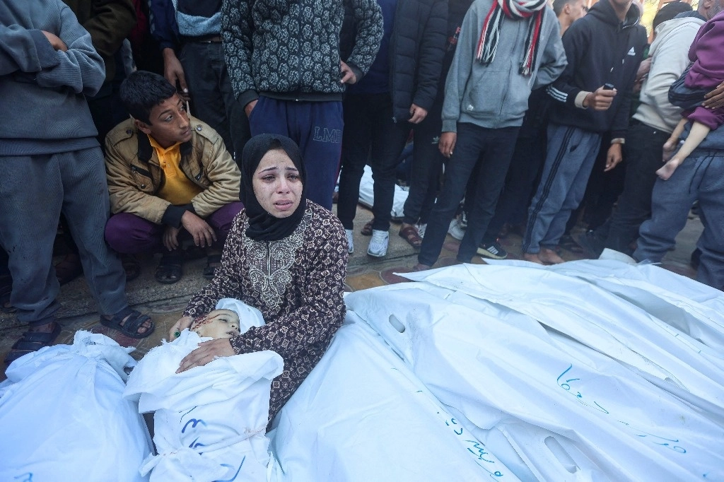 Una mujer llora ante el cuerpo de un niño muerto en el bombardeo israelí en Khan Yunis, en el sur de la Franja de Gaza, expuesto para que sus familiares lo identifiquen, frente a la morgue del hospital Nasser el 15 de diciembre de 2023. Foto Afp