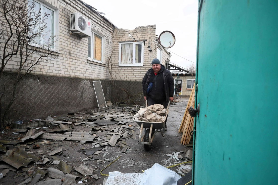 Un habitante de Stanytsia Luhanska, Ucrania, limpia escombros después de un bombardeo de los separatistas respaldados por Rusia, el 18 de febrero de 2022. Foto Afp