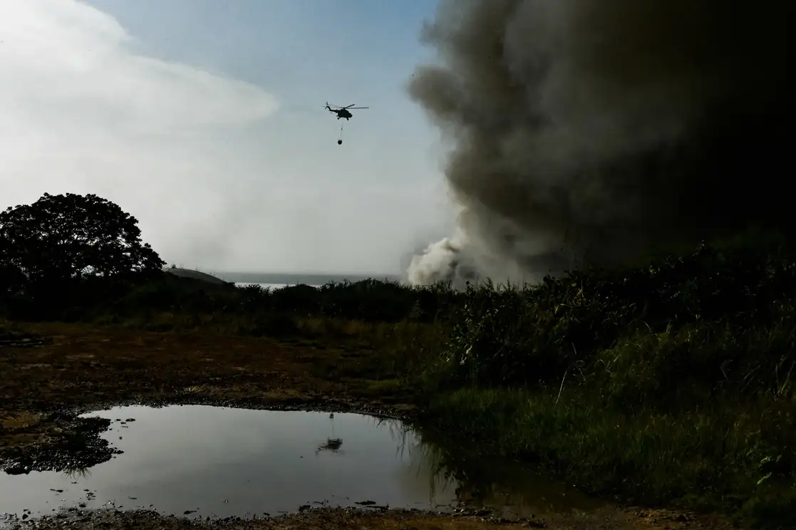 Un helicóptero de bomberos transporta agua para combatir un incendio masivo en un depósito de combustible provocado por un rayo en Matanzas, Cuba, el 9 de agosto de 2022. Foto Afp