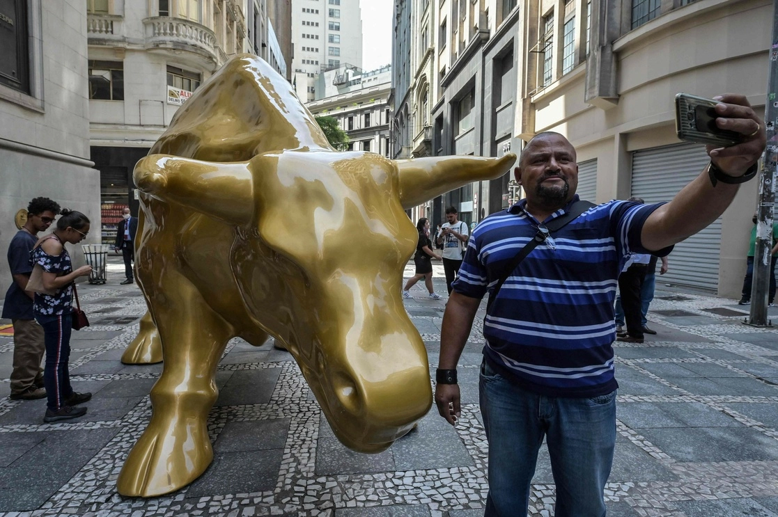 Un hombre se toma un foto con una escultura de un toro en una calle de Sao Paulo. Foto Afp