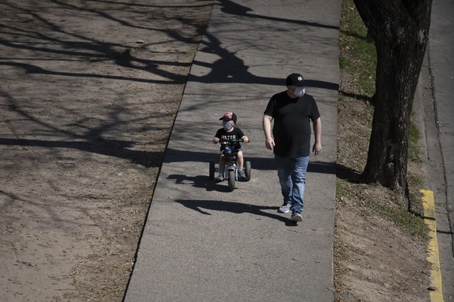 Un hombre y su hijo portan cubrebocas mientras pasean por un parque, en la ciudad de Buenos Aires,  Argentina. Foto Xinhua