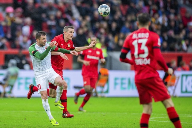 Sven Bender, del Bayer Leverkusen y Daniel Baier, del Augsburgo disputan el balón en la cancha del estadio Bay Arena. Foto Ap