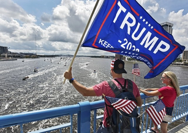 Partidarios de Donald Trump ondean una bandera de EU para celebrar el cumpleaños del presidente. Foto Ap 