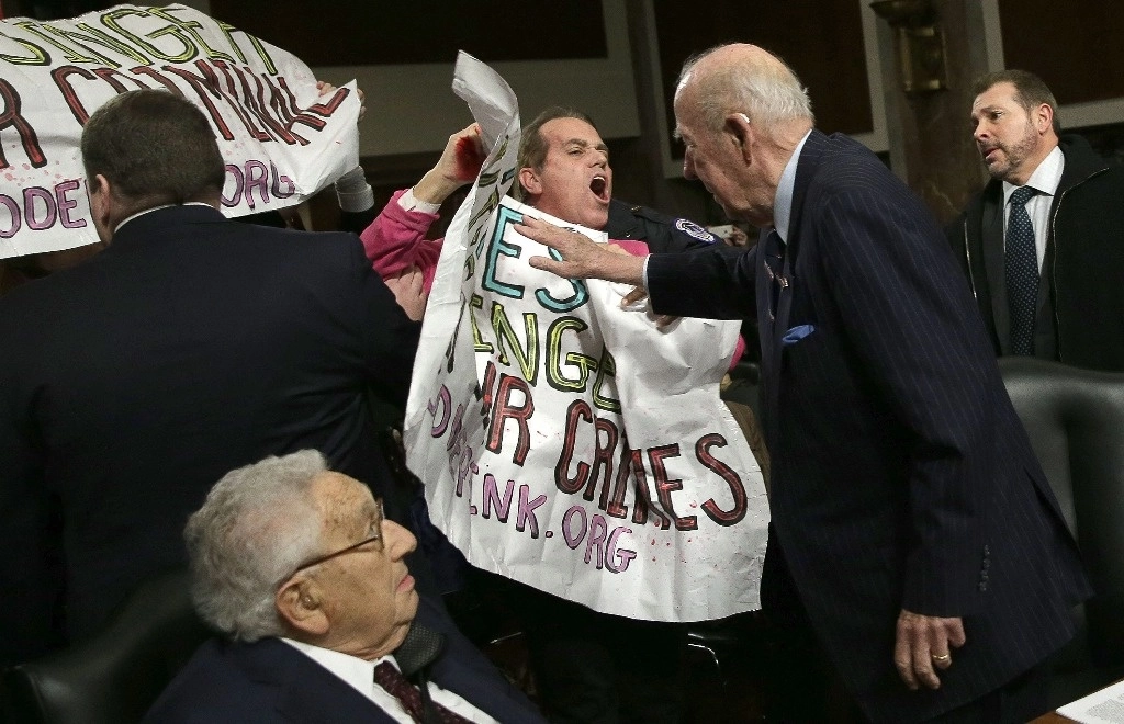El ex secretario de Estado George Shultz (derecha), empuja a manifestantes que gritan: Arresten a Henry Kissinger por crímenes de guerra, mientras Kissinger (izquierda) observa antes de que los dos testifiquen ante el Senado el 29 de enero de 2015 en Washington, DC. Foto Afp