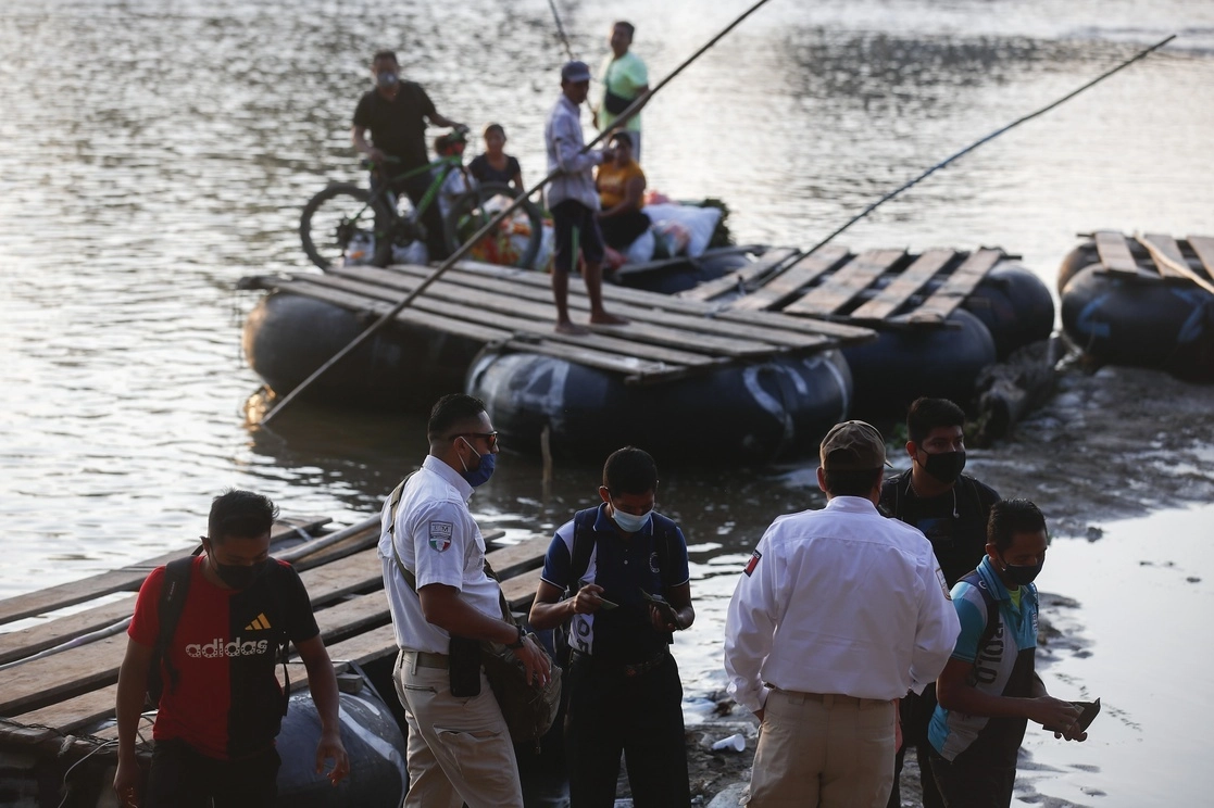 Personal de Migración revisa documentos a gente que atraviesa el río Suchiate en balsas provenientes de la ciudad guatemalteca de Tecún Umán, en Chiapas, el 22 de marzo de 2021. Foto Víctor Camacho