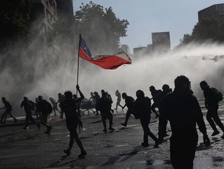 La policía lanzó durante horas chorros de agua a opositores al gobierno que protestaban en la Plaza de la Dignidad, en la ciudad de Santiago, previo a la consulta. Foto Ap