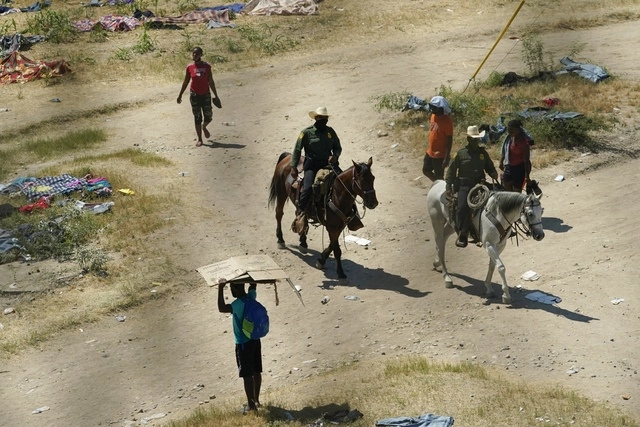 Agentes de la Patrulla Fronteriza pasan junto a migrantes haitianos en Del Rio, Texas. Foto Ap/Archivo