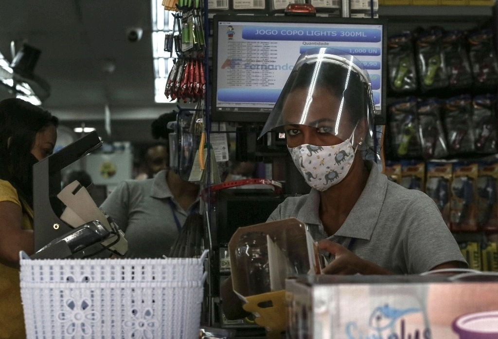 Una cajera porta una mascarilla y careta mientras trabaja en una tienda en Sao Paulo. Foto Xinhua