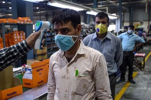 Toma de temperatura en una fábrica de calzado en el norte de India. Foto Afp