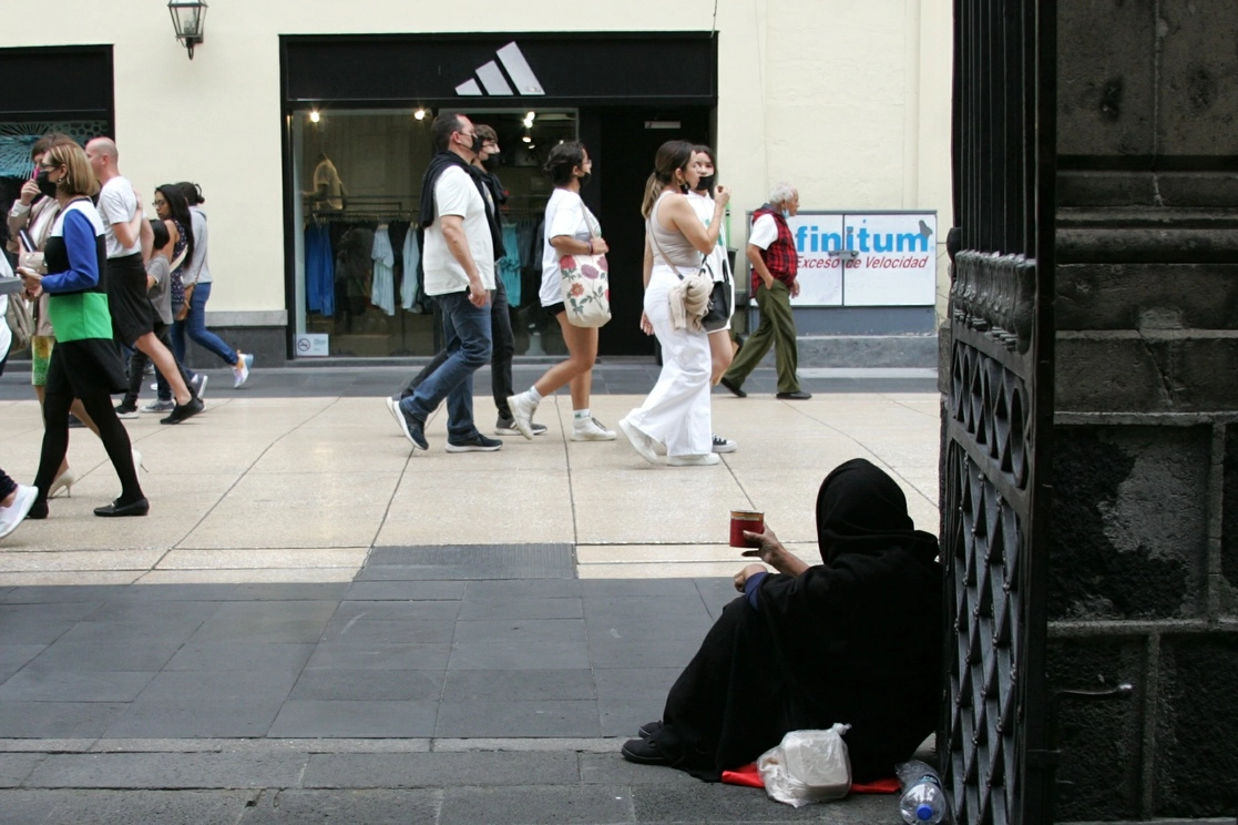 En un reporte, el Banco Mundial mostró que la pobreza en el país aumentó en 4.2 puntos porcentuales, respecto al nivel previo a la pandemia de coronavirus, alza que prácticamente no fue mitigada con políticas fiscales para atender la emergencia. En la imagen, una mujer pide limosna al exterior de la Iglesia de la Profesa, en el Centro Histórico capitalino. Foto Roberto García Rivas / Archivo
