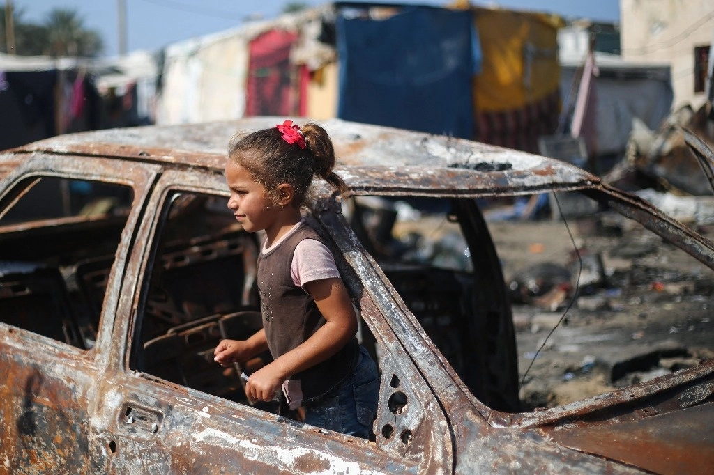 Una niña palestina encontró un sitio para jugar en los restos de un automóvil destruido por bombardeos de Israel en Deir el Balah. Foto Afp 
