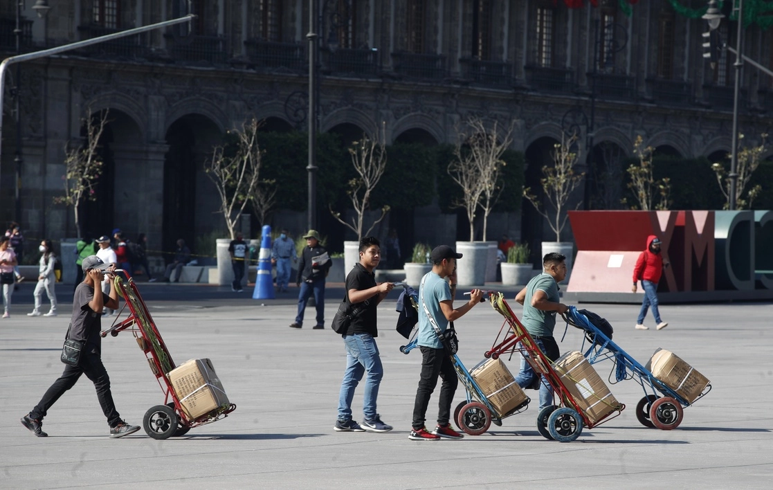 El llamado del gobierno es a continuar con las medidas preventivas, por lo que no se cerrarán las actividades económicas a pesar del gran número de contagios. En el Zócalo, 'diableros' desafían al virus, ya que van sin cubrebocas. Foto Cristina Rodríguez