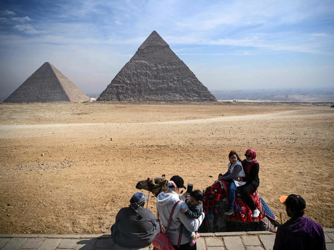 Un grupo de turistas se toman fotos frente a las pirámides de Keops y Chephren en la necrópolis de las pirámides de Giza, en las afueras de El Cairo, Egipto. Foto Afp