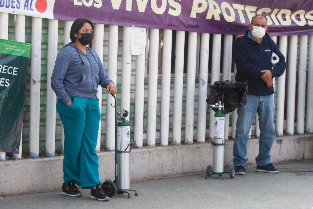 Personas aguardan su turno para rellenar tanques de oxígeno medicinal de manera gratuita, afuera de la alcaldía Iztapalapa. Foto Pablo Ramos